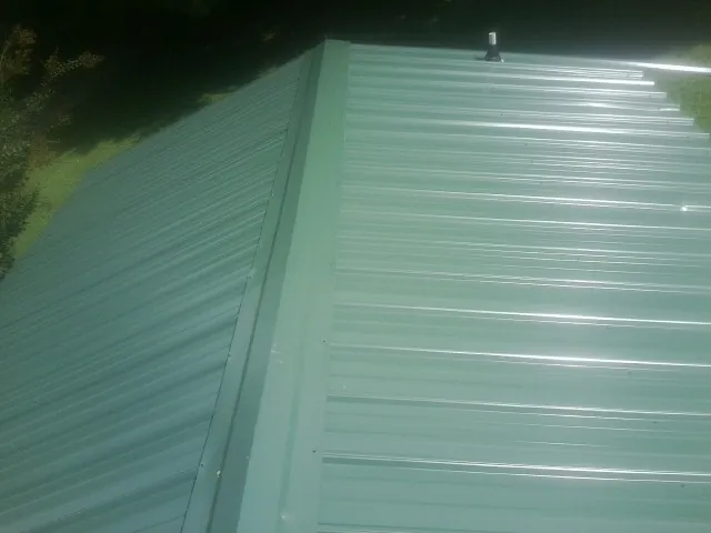 New green metal panels meeting at the ridge of a roof — Flat Roof Repair work by our crew in Copperhill