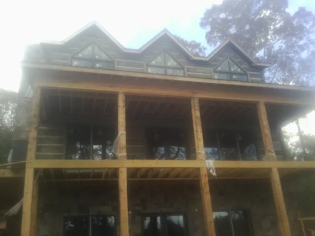 Dormers and porch framing on a large log home under construction — Roof Coating work by our crew in Copperhill