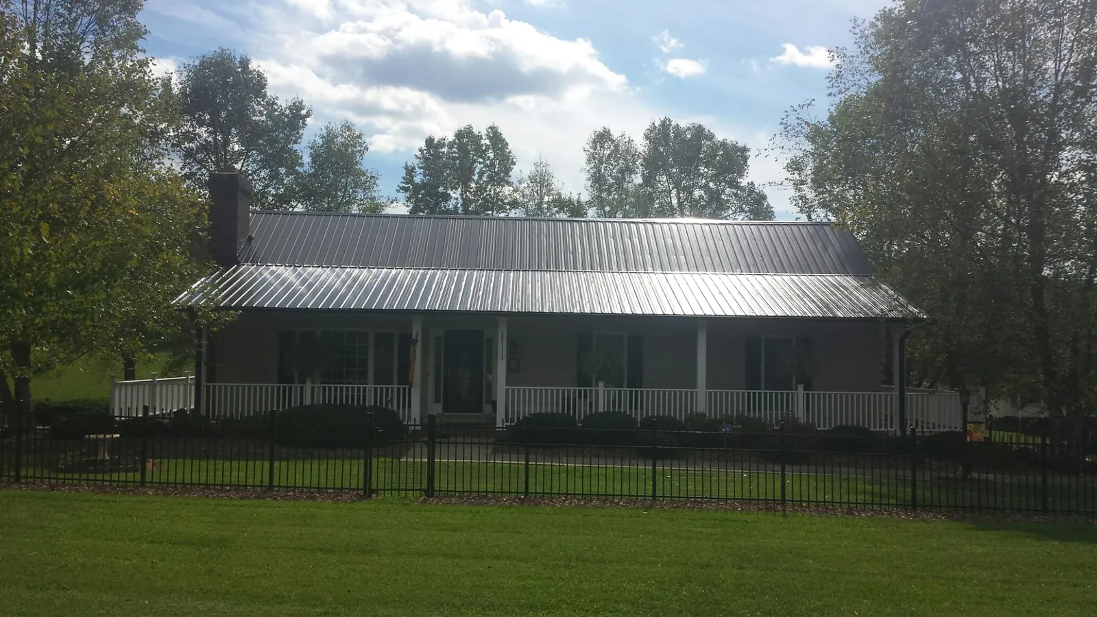 Gray metal roof on a brick ranch with a full width front porch — Gutter Guard Installation work by our crew in Copperhill