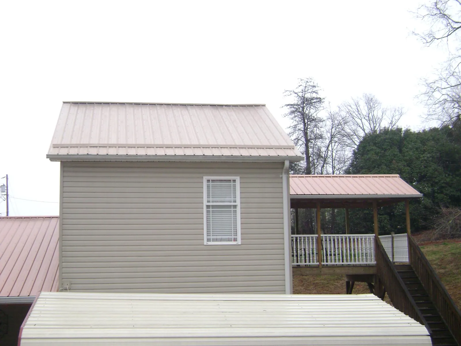 Tan metal roofs on a two story addition and attached porch, from a Roof Replacement job in Copperhill