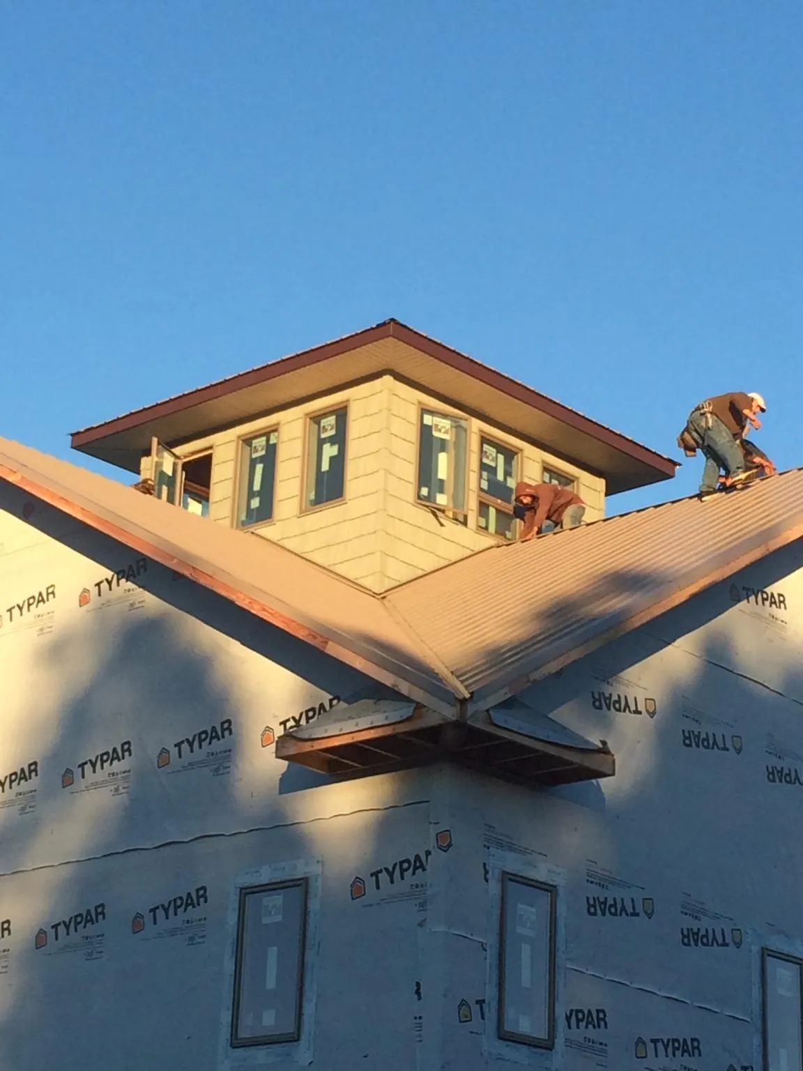 Roofers working around a rooftop cupola on a new metal roof at sunset — Roof Waterproofing in Copperhill by Roofing Brothers